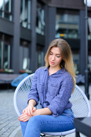 Pretty woman sitting at cafe outside and wearing blue shirt. Concept of urban life and leisure time.の写真素材