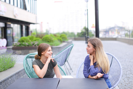 Pretty emale friends sitting at street cafe outdoors. Concept of having free time and open air.の写真素材