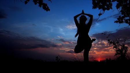 Shadow female silhouette in sunset background, woman doing yoga before sleeping. Concept of relaxing and asanas.の写真素材