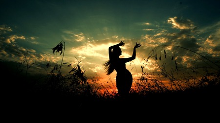 Female person dancing in steppe, silhouette in sunset background. Concept of dancing meditation and relaxing on nature.の写真素材