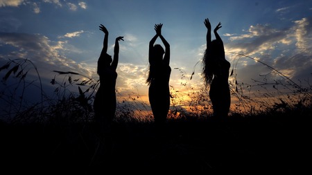 Female shadow silhouettes doing yoga in steppe, sunset background. Concept of asanas and meditation...