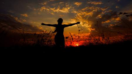 Female dark shadow silhouette in sunset steppe background. Concept of doing yoga and asanas...
