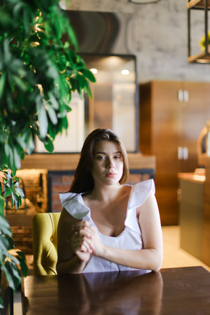 Beautiful young photo model resting at cafe and wearing white blouse with silver ring. Concept of beauty and rest.の写真素材