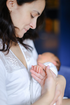 Young aucasian mother holding newborn baby. Concept of motherhood and babies.の写真素材
