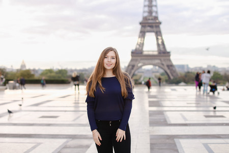 Beautiful woman standing in Eiffel Tower background in Paris. Concept of famous landmarks in France and tourism.の写真素材