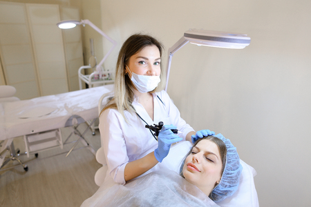 Lady getting qualified tattooing eyebrows procedure by cosmetologist. Concept of beauty salon and permanent makeup.の写真素材