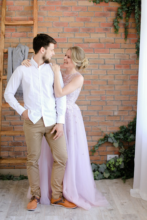 Groom and blonde bride standing with brick wall background. Concept of wedding and happy couple.の写真素材