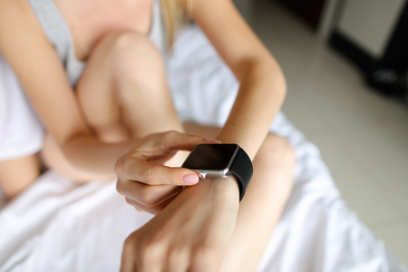 Close up female arms with smart watch in white linen background. Concept of modern gadgets and technology.の写真素材