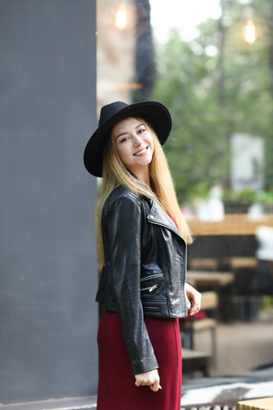 Young girl wearing black hat and red dress, and leather jacket.. Concept of fashion and european youth.の写真素材