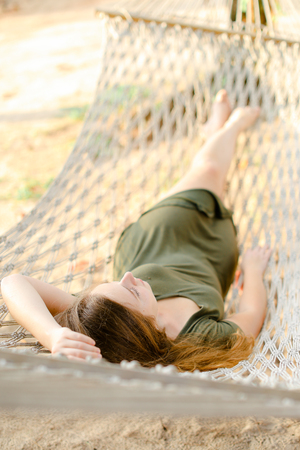 Young woman lying in wicker hammock on beach. Concept of relaxation and vacations on tropic islands.の写真素材
