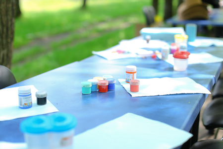 Gouache paints on blue table in park. Concept of art and camp.の写真素材