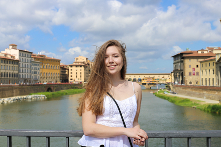 Female tourist in Arno river and buildings background in Florence. Concept of cheapest tours to Italy and spending summer vacations in Europe.の写真素材