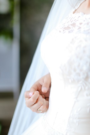 Closeup bridal white dress and hand. Concept of wedding photo session.の写真素材