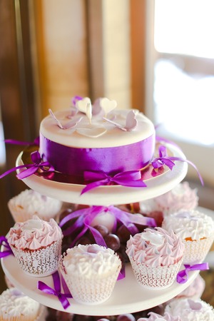 Violet decorations and sweet yummy cakes for party. Concept of birthday sweets and tasty food.の写真素材