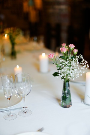 Bouguet of flowers, plates and white candles on table. oncept of romantic dinner and catering establishment.の写真素材