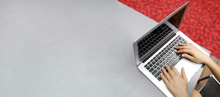 Website banner of laptop with female hands, copy space in grey color and red background. Concept of...