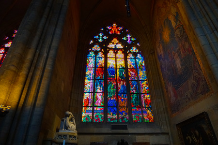 Inside st. Vitus. Cathedral and stained glass with Catholic icons. Concept of religious Gothic style interior decorations.のeditorial素材