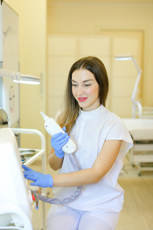 Caucasian permanent makeup artist sitting with laser removal of tatoos device at beauty salon. Concept of cosmetology equipment and cosmetologist.の写真素材