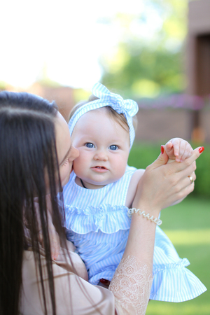 Closeup young aucasian mother holding little female child in blue dress. Concept of motherhood and child.の写真素材