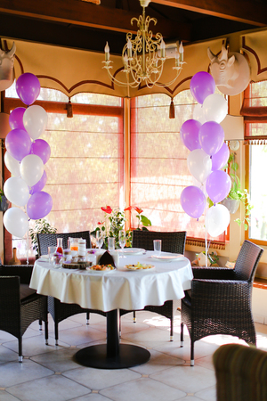 Food on table at cafe and white violet ballons. Concept of preparations for birthday.の写真素材