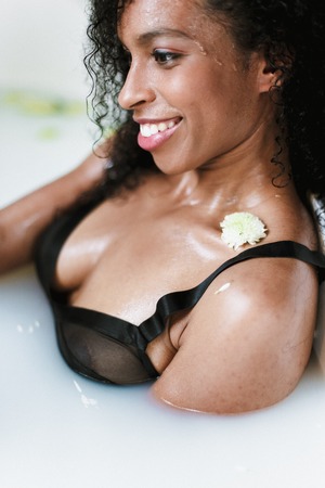 Close up photo of black woman taking bath with foam, wearing swimsuit. Concept of beauty and relax,...