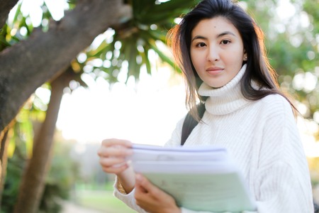 Focus on korean girl keeping documents and walking outdoors. Concept of asian student.