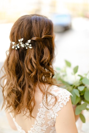 Back view of nice brown curls for bride keeping flowers. Concept of wedding photo session and stylish hair do.の写真素材