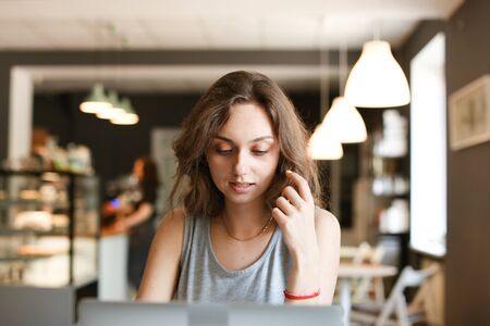 Young nice girl working with laptop at cafe. Concept of modern technology and free hotspot, fast internet and social networks.の写真素材
