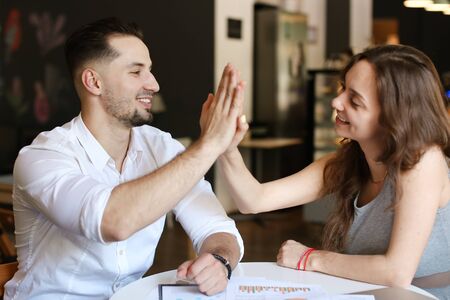 Successful businessman and woman working with documents and diagrams, giving high five. Concept of...
