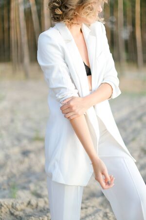 Blonde pretty girl in white clothes walking on sand beach and wearing white clothes. Concept of summer vacations.の写真素材