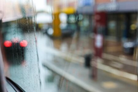 Rainy glass and street lights in background. Concept of rain in town, blurred street.の写真素材