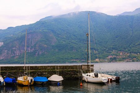 Little boat port with Alps mountain in background, lake Como in Mandello del Lario. Concept of landcape and nature, summer vacations.の写真素材
