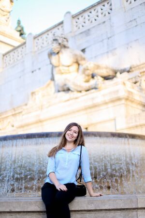Young girl sitting near Trevi fountain, wearing blue shirt. Concept of traveling to Italy, Rome and youth.の写真素材