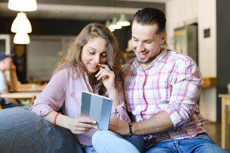Young nice wife and husband using tablet and free hotspot at cafe. Concept of modern technology, fast internet and happy couple.の写真素材