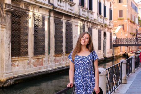Young girl sitting on banister in Venice, Italy. Concept of last minute tours to Europe and romantic venetsian street.の写真素材
