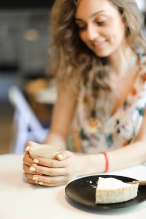 Young girl sitting with cup of coffee at cafe, focus on cake. Concept of having lunch and resting at break.の写真素材