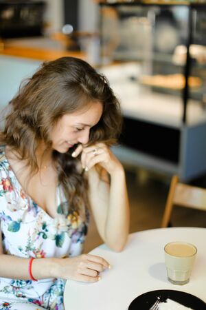 Young happy woman with cup of coffee sitting at cafe and resting. Concept of having kunch and resting at break.の写真素材