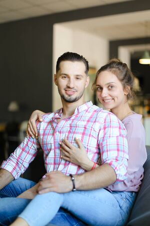 Young cute nice girl hugging boyfriend indoors and smiling. Concept of happy couple, relationship and love.の写真素材