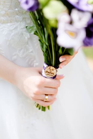 Closeup bridal hands keeping violet bouquet of flowers. Concept of wedding photo session and floristic art.の写真素材