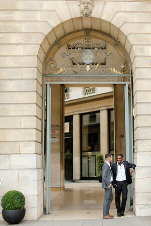 Two happy men, caucasian and afro american, wearing suits speaking near building outdoors. Concept of successful business partners.の写真素材