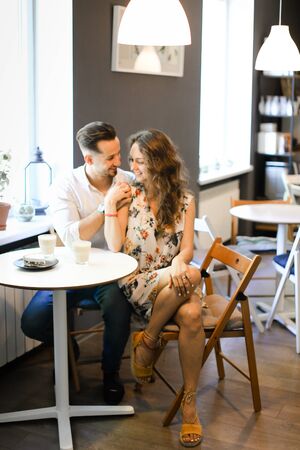 Young happy boyfriend hugging girl and sitting at cafe and resting. Concept of pleasent feelings and resting with lunch.の写真素材