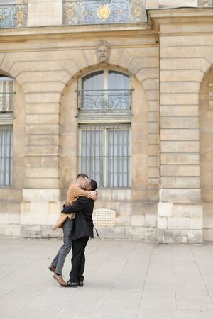 Afro american man holding caucasian guy and waling in building background. Concept of gays and same sex couple.の写真素材