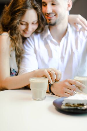 Young girl hugging man and sitting at cafe with cup of coffee and cake. Concept of feelings, lunch and happy couple.の写真素材