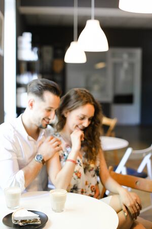 Young caucasian man hugging woman at cafe, ,sitting near cups of coffee. Concept of positive emotions, feelings and resting on lunch.の写真素材