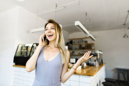 Housewife standing in kitchen and talking by smartphone. Concept of happy wife and modern...