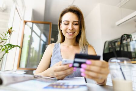 Focus on happy girl using smartphone and credit card for paying online. Concept of booking tickets and tours.の写真素材