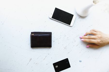 Smartphone, leather wallet and credit card lying near female hand. Concept o modern technology and paying online.の写真素材