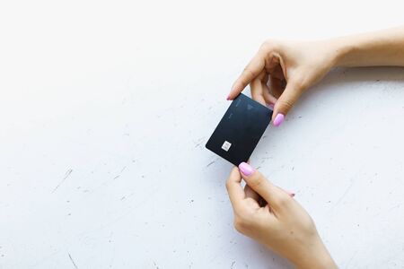 Hand with pink nails keeping black debit card in white background. Concept of bank account and credit.の写真素材