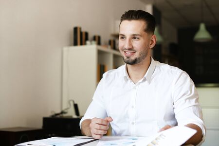 Young male manager working with papers and wearing white shirt. Concept of business and job.の写真素材