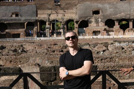 Young male tourist wearing black clothes inside Colosseum in Rome, Italy. Concept of last minute tours to Europe and visiting ancient landmarks.の写真素材